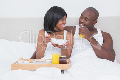 Pretty couple taking breakfast in bed together