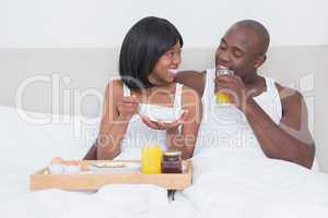 Pretty couple taking breakfast in bed together