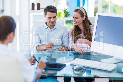 Pregnant woman and her husband looking at picture of their futur