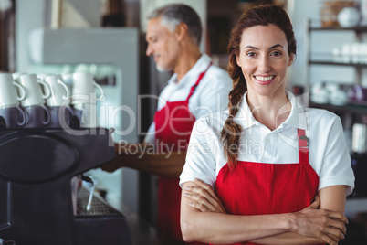 Pretty barista smiling at camera with colleague behind