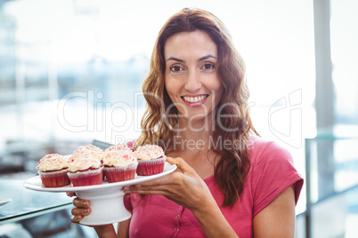 Pretty brunette showing plate of pastries