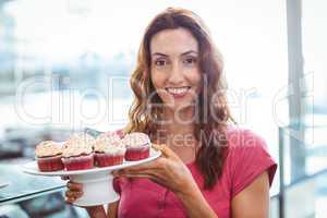 Pretty brunette showing plate of pastries