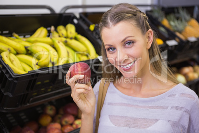 Pretty blonde woman showing a red apple