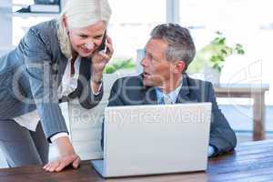 Businesswoman having phone call and looking at laptop