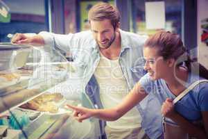 Young happy couple choosing cake