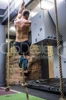 Back view of muscular man doing rope climbing