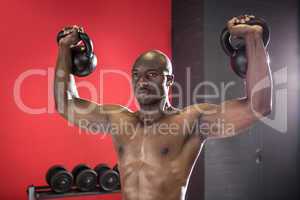 Muscular man lifting two kettlebells