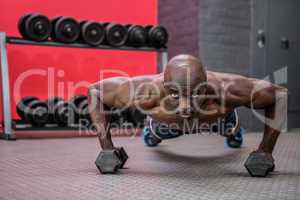 Portrait of muscular man doing push-ups with dumbbells