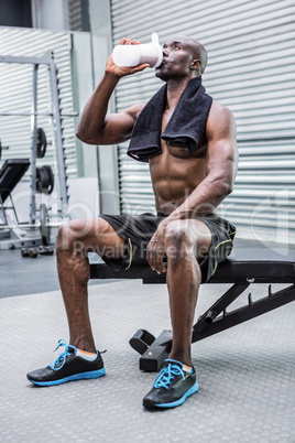 Young Bodybuilder drinking a bottle of water after the training