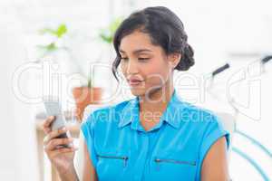 Casual businesswoman text messaging in office