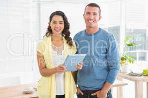 Portrait of smiling colleagues with tablet computer looking at c