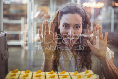 Pretty brunette looking at pastries through the glass