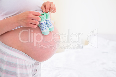 Pregnant woman holding baby shoes over bump