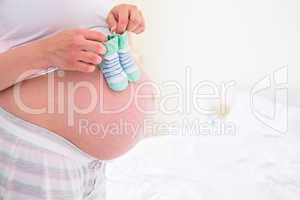 Pregnant woman holding baby shoes over bump