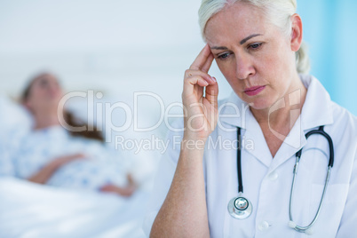 Worried female doctor looking away while her patient resting