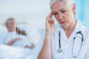 Worried female doctor looking away while her patient resting