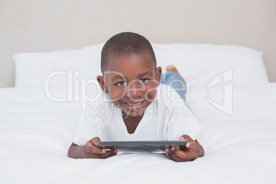 Portrait of a pretty little boy using digital tablet in bed