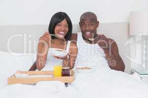 Portrait of a pretty couple taking breakfast in bed together