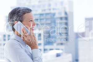 Businesswoman looking through window while on the phone