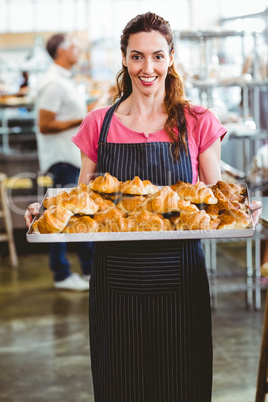 Baker showing tray of fresh croissant