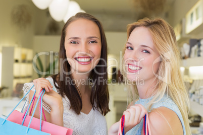 Happy women friends smiling at camera with shopping bags