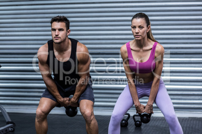 A muscular couple lifting kettlebells