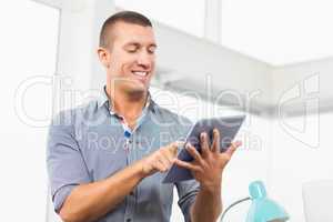 Smiling businessman scrolling on his tablet