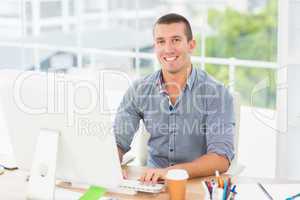 Handsome smiling businessman typing on a computer