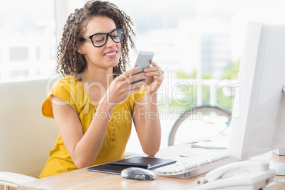 Smiling young businesswoman sending a text