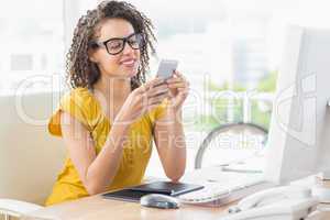 Smiling young businesswoman sending a text