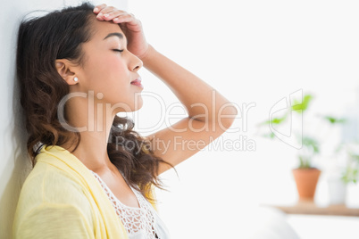 Young thinking businesswoman leaning against a wall