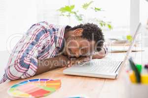 Young businessman sleeping in front of his laptop