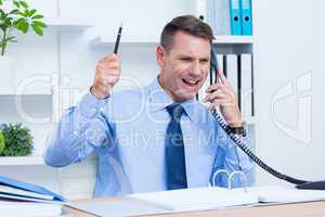 An angry businessman phoning at his desk