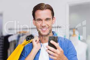 A smiling man with shopping bags looking at his smartphone