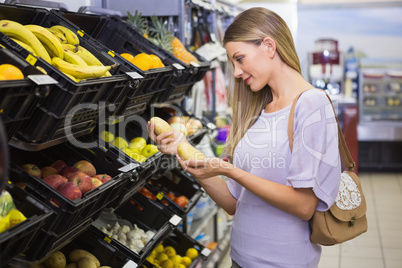 Smiling pretty blonde woman buying potatoes