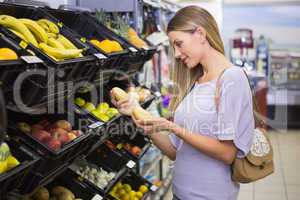 Smiling pretty blonde woman buying potatoes