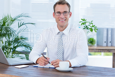 Smiling businessman writing on notebook