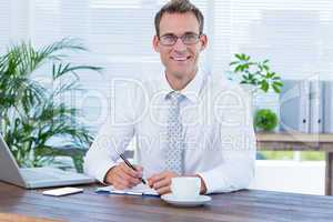 Smiling businessman writing on notebook