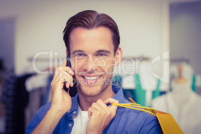 A smiling man with shopping bags calling