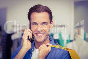 A smiling man with shopping bags calling