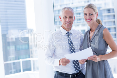 Smiling business people talking over a paper sheet