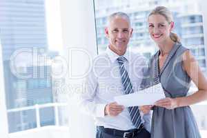 Smiling business people talking over a paper sheet