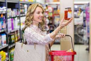 Side view of a smiling pretty blonde woman looking at a product