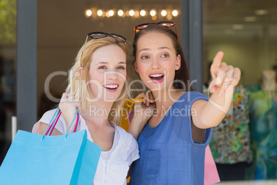 Smiling girls friends pointing away