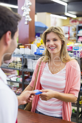 Smiling woman at cash register paying with credit card