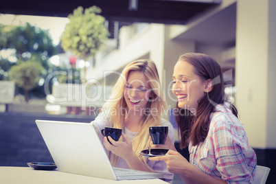 Happy women friends looking at laptop