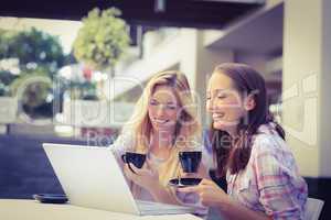 Happy women friends looking at laptop