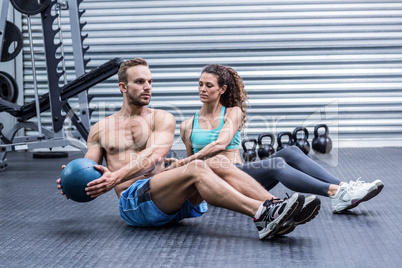 Muscular couple doing abdominal ball exercise