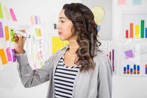 Young serious businesswoman writing on sticky notes