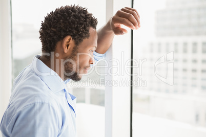 Young thoughtful businessman leaning against a window